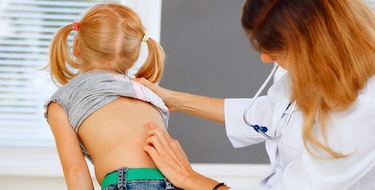 un médecin examine le dos d'un enfant à la recherche de douleurs lombaires